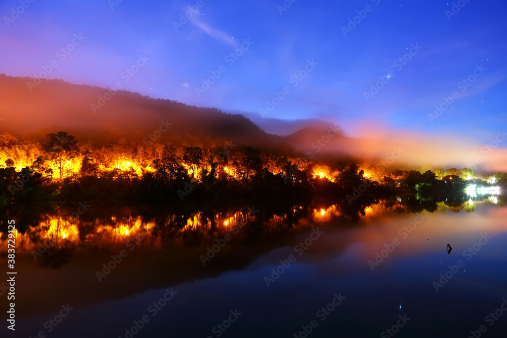 A beautiful landscape reflecting water, roadside lights and the sky with light mist in the early morning