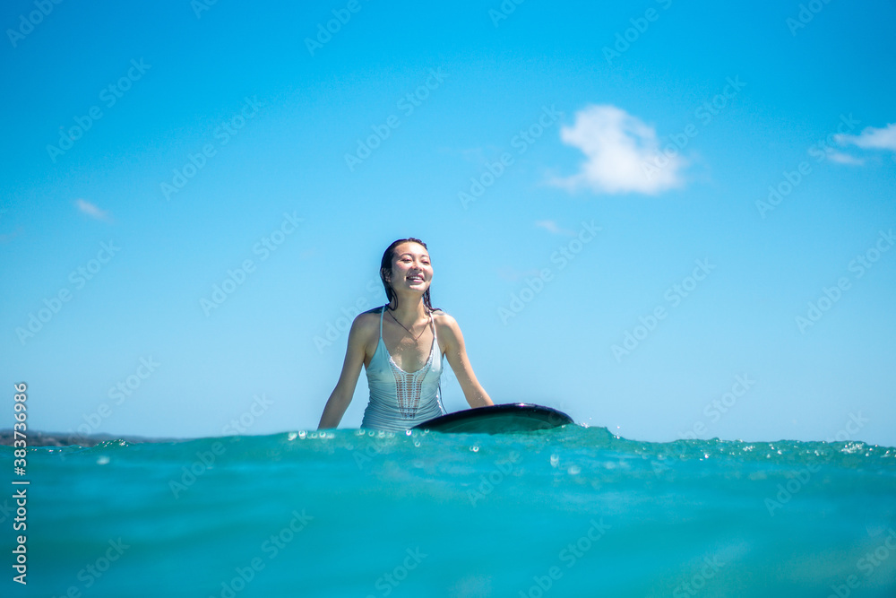 Portrait of surfer girl on surf board in blue ocean