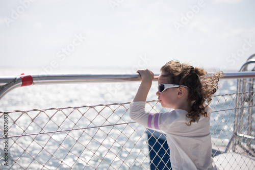 Photo Young girl from behind on a boat railing handrail looking out over the ocean and