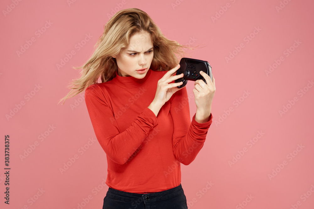 Woman with gamepad in hand entertainment video games lifestyle technology red blouse pink background Woman with gamepad in hand entertainment video games lifestyle technology red blouse pink background