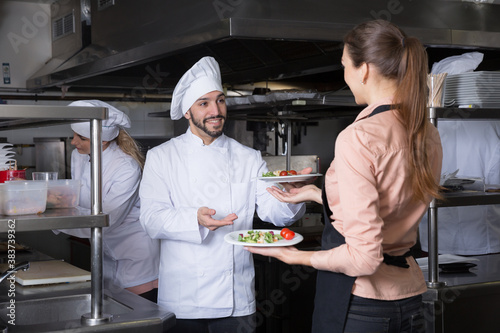 Head chef checking dishes in kitchen of restaurant before serving guests