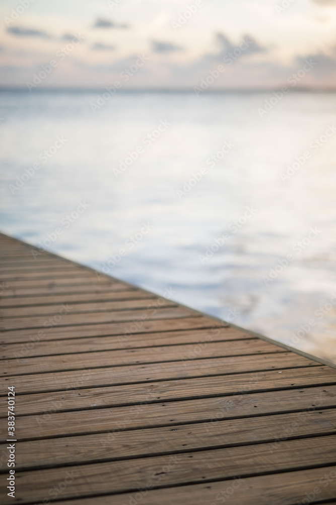 Timber deck platform with blue water ocean in the background and sky clouds