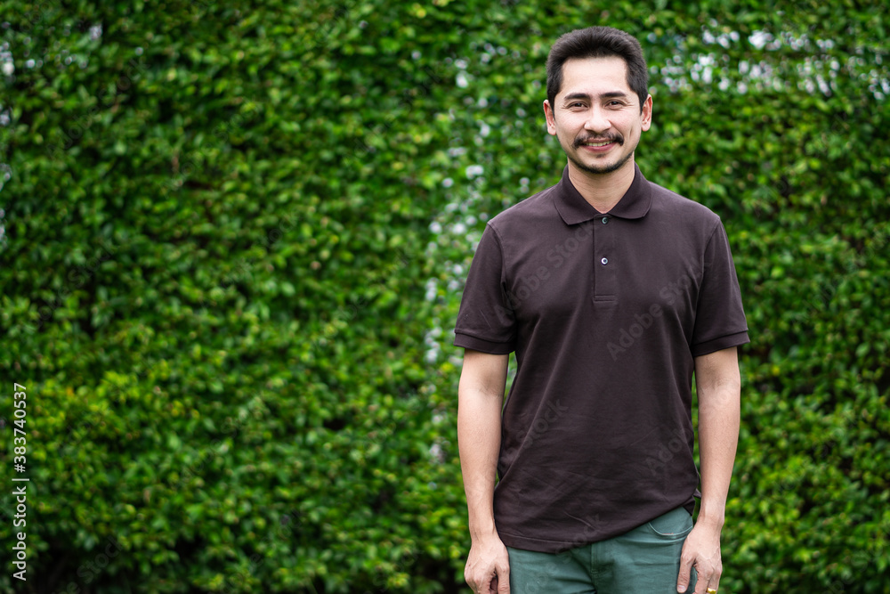 Young man asian smiling and looking out. Portrait of a happy handsome young man on green nature background. Young cool trendy. Young man asian smiling and looking out. Portrait of a happy handsome young man on green nature background. Young cool trendy.