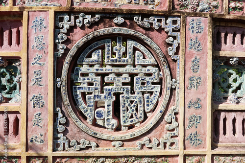Hoi An, Vietnam, February 23, 2020: Detail of a wall with colorful decoration in the garden of the Chùa Phước Lâm temple. Hoi An, Vietna