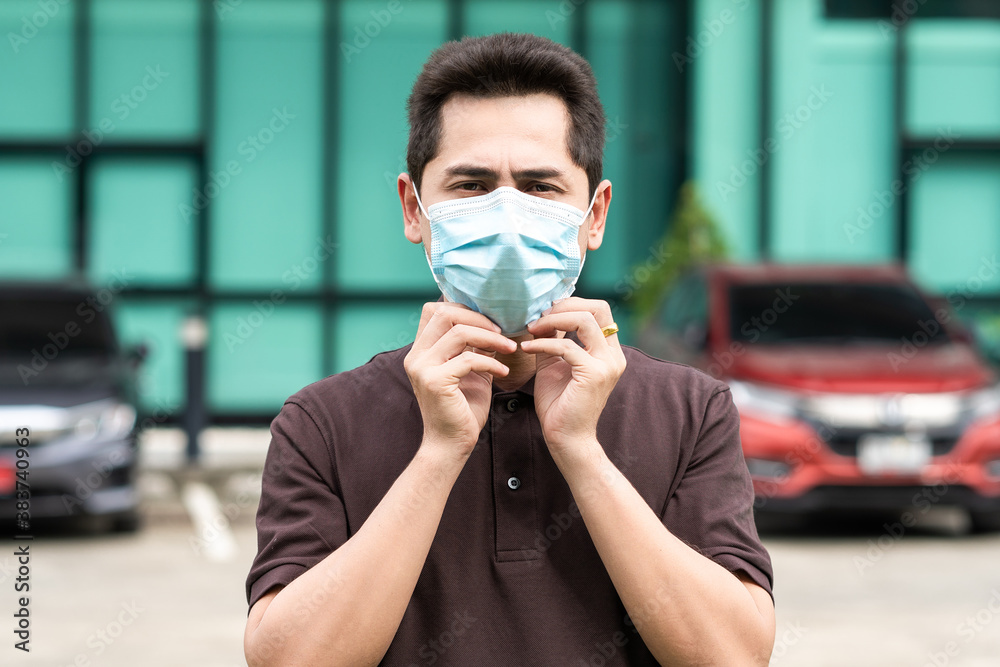 Handsome young man standing outdoors wearing medical mask to protect others from virus spread