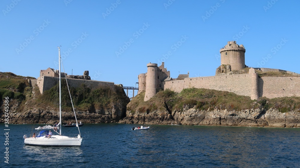 Fort la Latte ou château de la Roche Goyon, dans les Côtes-d'Armor en Bretagne, au bord de la mer, avec un voilier (France)