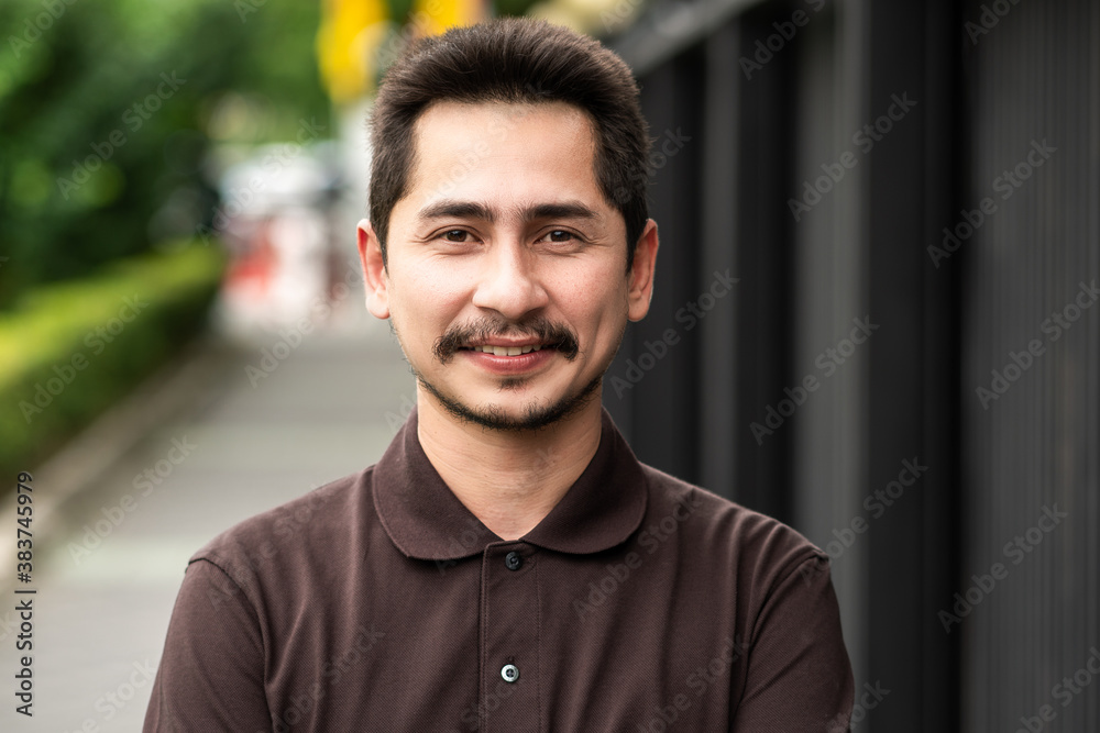 Young man asian smiling and looking at camera. Portrait of a happy handsome young man in a urban street. Close up face of young cool trendy man looking at camera Young man asian smiling and looking at camera. Portrait of a happy handsome young man in a urban street. Close up face of young cool trendy man looking at camera
