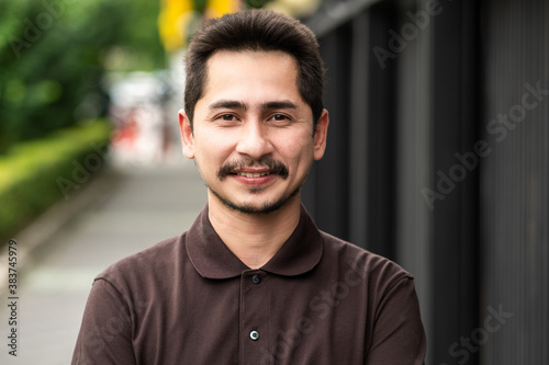 Young man asian smiling and looking at camera. Portrait of a happy handsome young man in a urban street. Close up face of young cool trendy man looking at camera