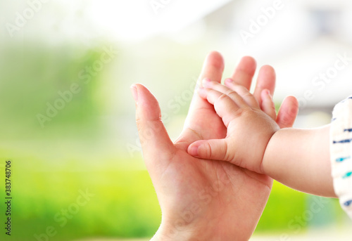 母親と赤ちゃんが手をつなぐ　親子の触れ合い © minianne