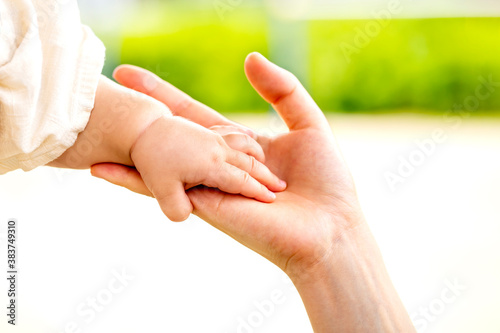 母親と赤ちゃんが手をつなぐ　親子の触れ合い © minianne