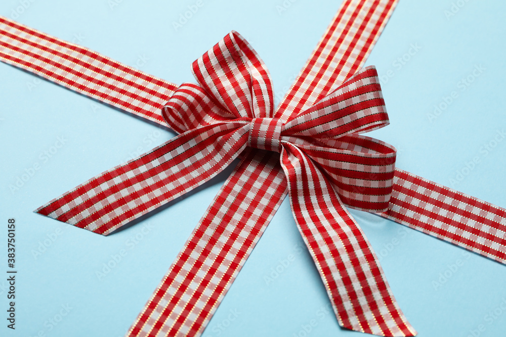 Checkered gift bow on blue background, close up