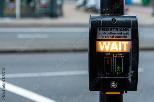 Crosswalk button for pedestrian with light warning on a defocused background , London, UK