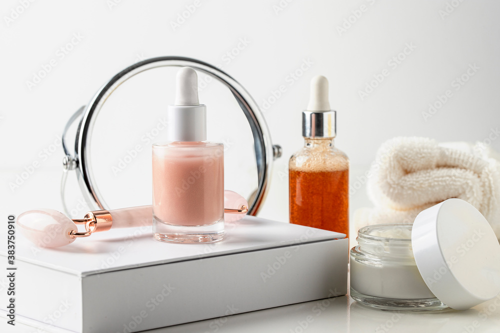 Natural cosmetic, serum with essential oil and vitamins, homemade cream and massage stone roller with mirror on white background. Home skin care routine and beauty concept. Natural cosmetic, serum with essential oil and vitamins, homemade cream and massage stone roller with mirror on white background. Home skin care routine and beauty concept.