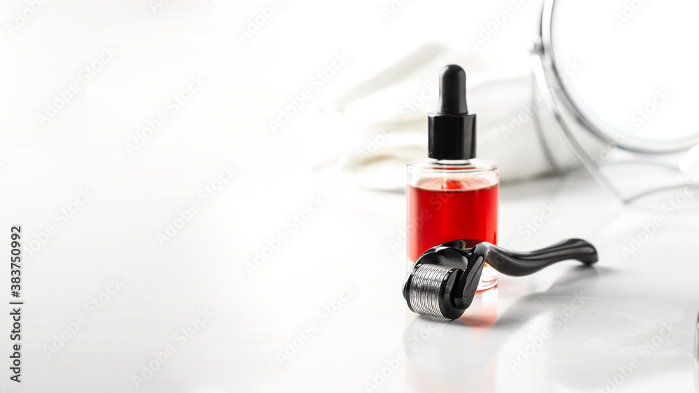 Face serum, mesoroller, towel   and mirror on white table for anti age skin care.Banner with copy space