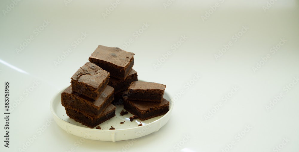 Chocolate brownie sliced into square slices on a white plate. Chocolate brownie sliced into square slices on a white plate.