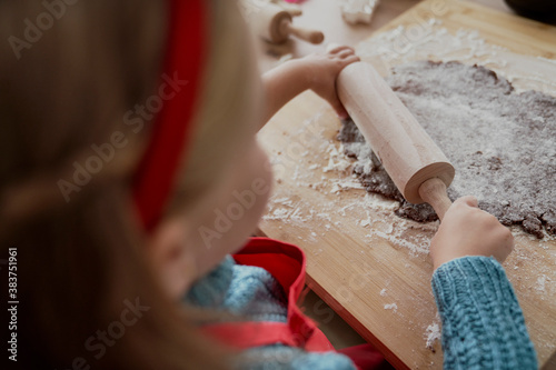 Rear view of little girl rolling gingerbread dough