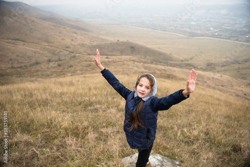 happy little caucasian girl in hoodie during mountain hiking leisure activity