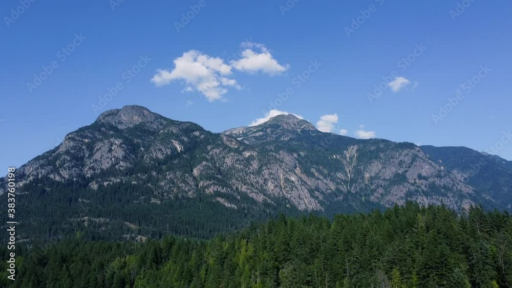 Epic shot of mountain with green trees on a sunny day and rare clouds Epic shot of mountain with green trees on a sunny day and rare clouds
