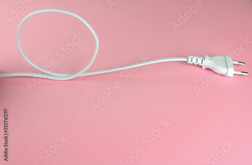 White power cord with plug on pink background, copy space