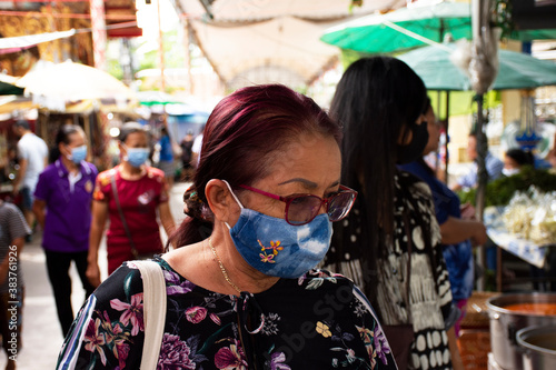 Thai senior mother wearing fabric mask for travel visit market and respect praying buddha while Coronavirus COVID 19 outbreak at Wat Bang Phli Yai Nai Temple on July 12, 2020 in Samut Prakan, Thailand