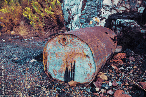 Bidón oxidado de alquitrán con vertido en el suelo