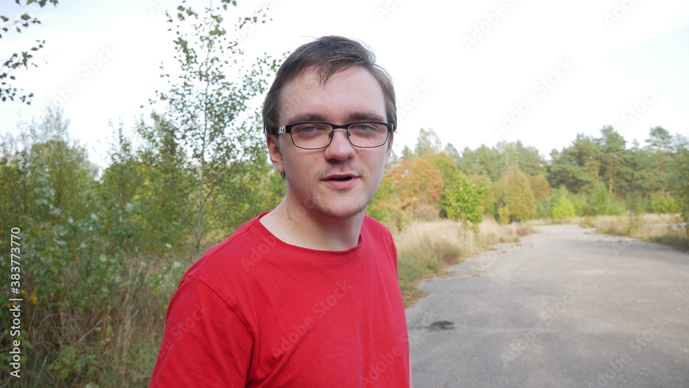 Young guy in a red t-shirt with glasses on the background of nature Young guy in a red t-shirt with glasses on the background of nature