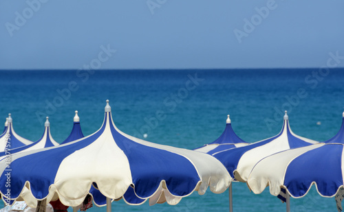 Umbrellas and deckchairs in the relaxation of the beaches of Sardinia wrapped in Mediterranean vegetation. photo