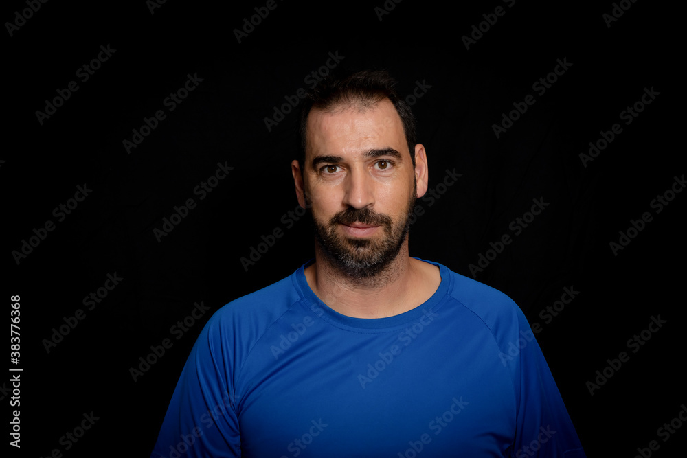 Bearded man dressed in blue t-shirt posing against black background Bearded man dressed in blue t-shirt posing against black background