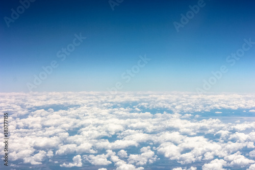 View from the plane window to cumulus clouds and blue sky. © Irida