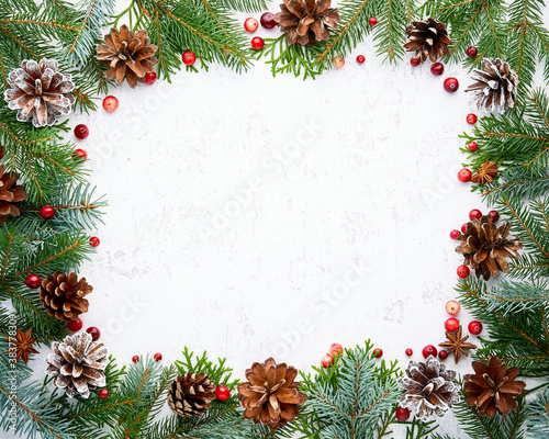 Christmas and Happy New Year light white background. Frame with fir branches, berry, cones. Stone backdrop with copy space.