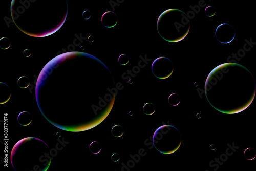 Flowing rainbow soap bubbles on isolated black background with copy space.