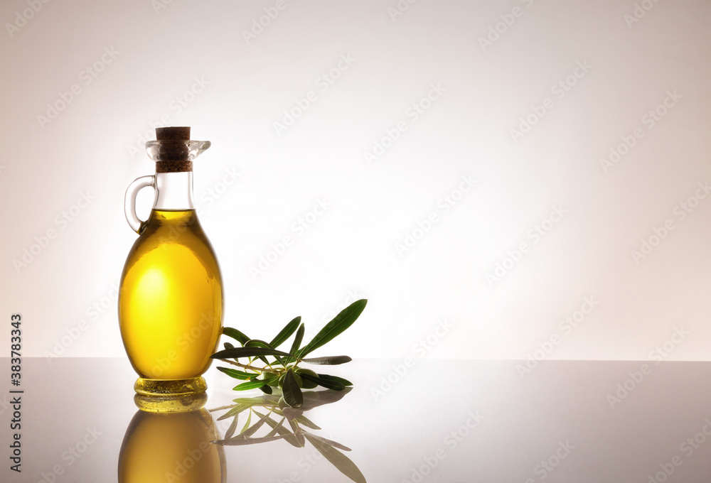 Glass container with oil and olive twig backlit on table Glass container with oil and olive twig backlit on table