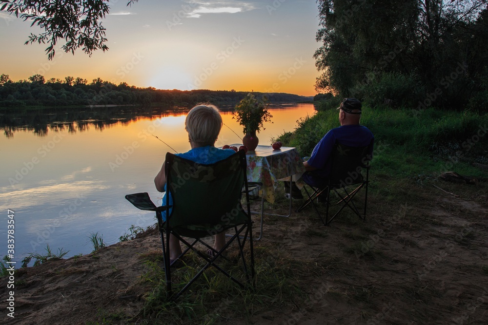 Elderly married couple admiring the sunset on the river