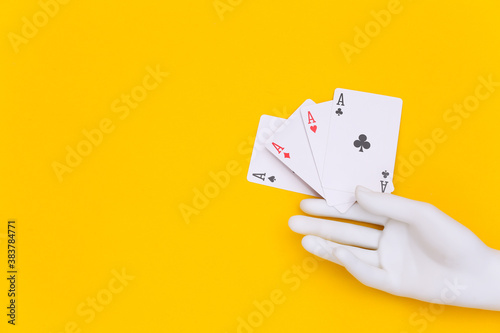 Four aces in mannequin hand on yellow background photo