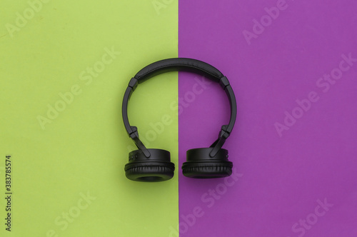 Wireless stereo headphones on green purple background. Top view