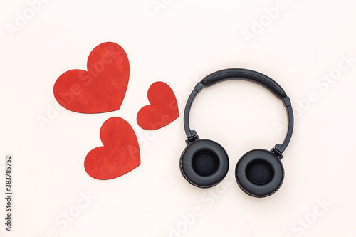 Music lover. Stereo headphones and hearts on a beige background. Top view
