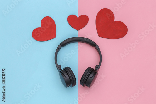 Music lover. Stereo headphones and hearts on pink blue pastel background. Top view