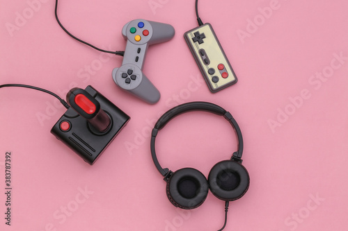 Stereo headphones and retro joysticks on a pink pastel background. Top view. Flat lay