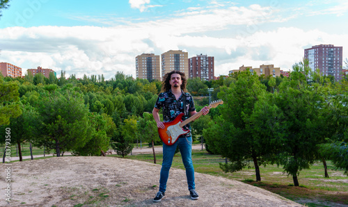 Músico con guitarra eléctrica en paisaje urbano