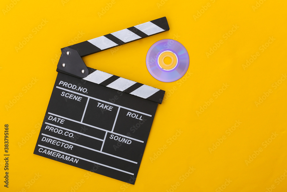 Film clapper board and cd on yellow background. Cinema industry, entertainment. Top view