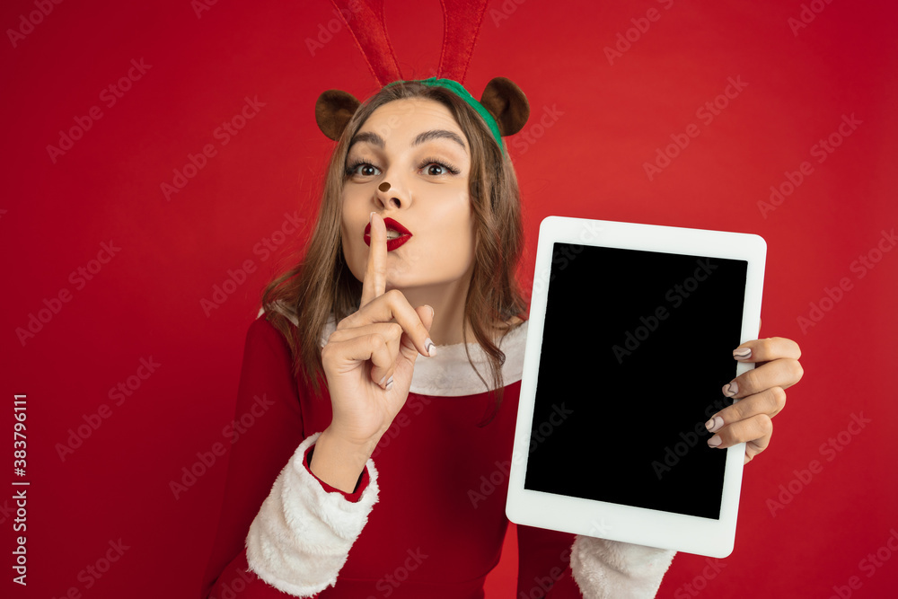 Showing blank tablet screen. Concept of Christmas, 2021 New Year's, winter mood, holidays. Copyspace for ad, postcard. Beautiful caucasian woman with long hair like Santa's Reindeer catching giftbox. Showing blank tablet screen. Concept of Christmas, 2021 New Year's, winter mood, holidays. Copyspace for ad, postcard. Beautiful caucasian woman with long hair like Santa's Reindeer catching giftbox.