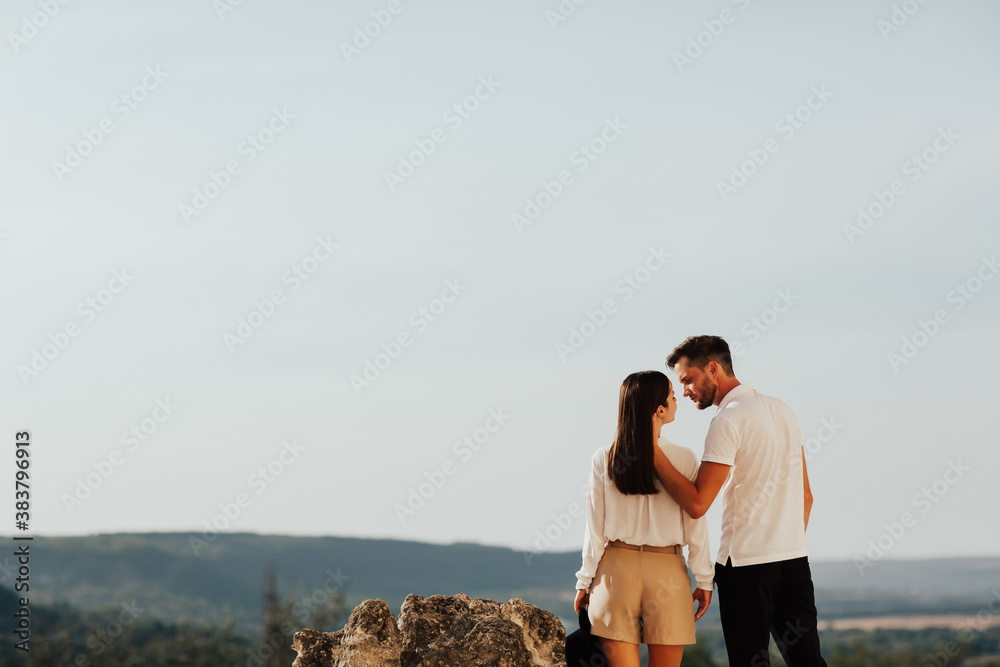 Couple enjoying mountain scenery. Loving couple are hugging on the mountain outdoors. Man and woman travel together. Couple traveler enjoys nature. Copy space.