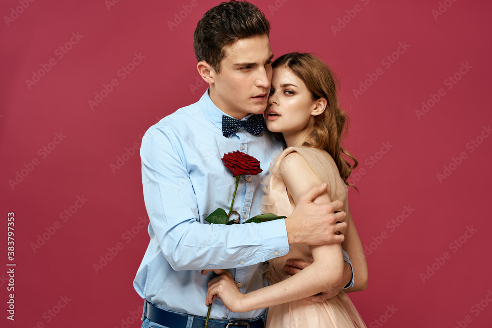 enamored man and woman with a red flower on a pink background hug each other Copy Space enamored man and woman with a red flower on a pink background hug each other Copy Space