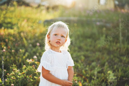 Cute blonde toddler little girl on green grass background, the country side, cottagecor