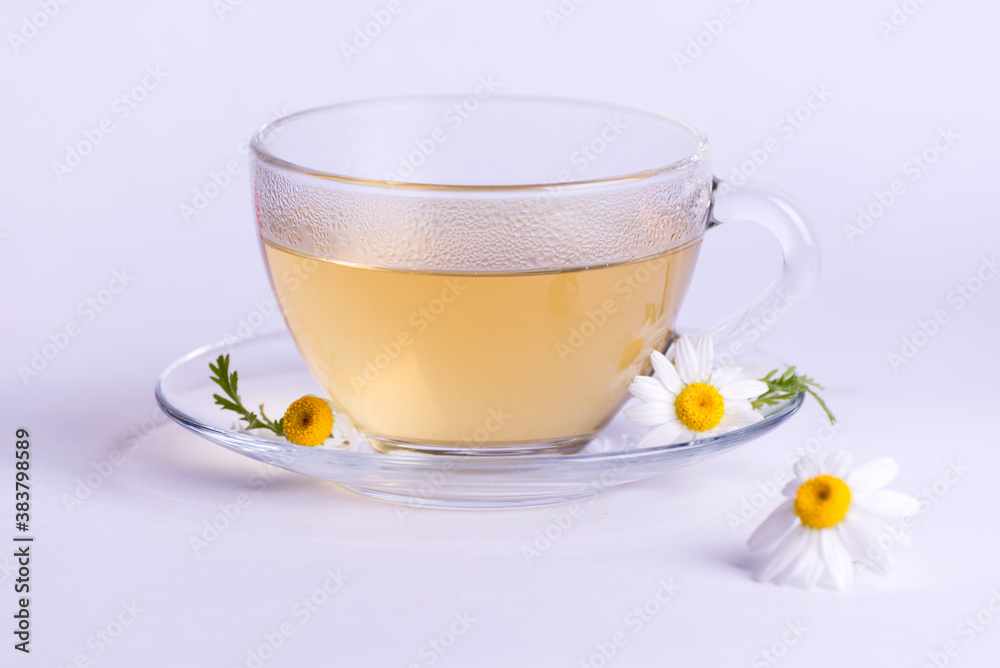 Cup of hot herbal tea with chamomile flowers against a light background. Cup of hot herbal tea with chamomile flowers against a light background.