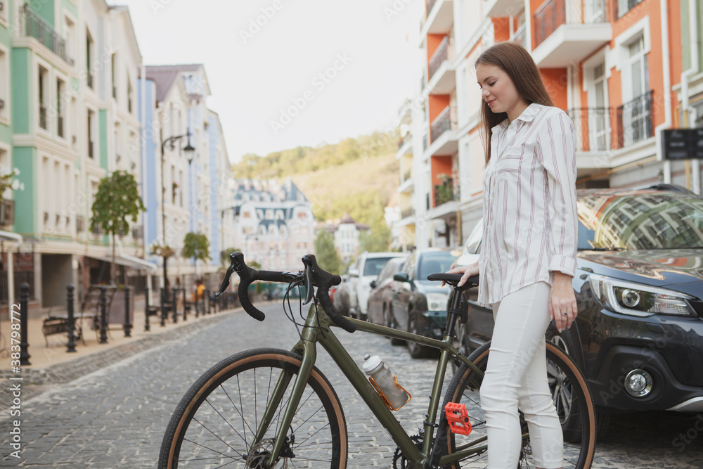 Attractive happy woman smiling, crossing the road with her bicycle, copy space