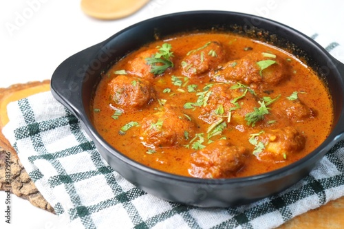Indian cuisine - Kashmiri Dum Aloo or Potatoes in red gravy over white background. Garnished with coriander. Serve hot with rice or Naan/roti. Copy space. Panjabi Dam alu curry.