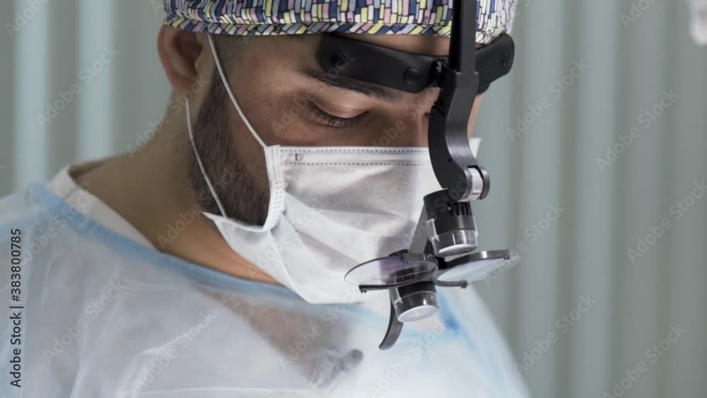 Portrait of a surgeon with magnification glass during the procedure in