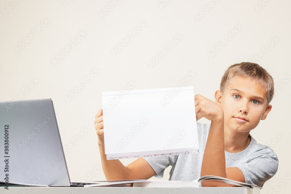 Kid hands holding open notebook with blank white pages Boy sitting at table with books and laptop computer Kid hands holding open notebook with blank white pages Boy sitting at table with books and laptop computer