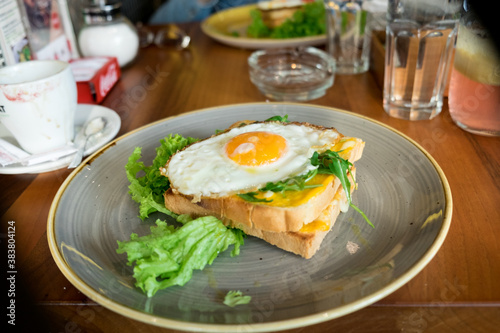 Healthy protein breakfast - crispy toasted bread with fried egg, bacon and fresh lettuce and cherry tomato